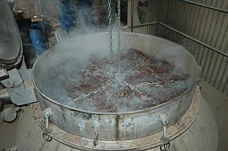 Cuve industrielle de distillation de bois de santal, dégageant de la vapeur