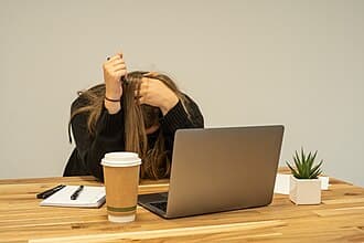 Femme stressée devant son ordinateur portable, tenant sa tête entre ses mains