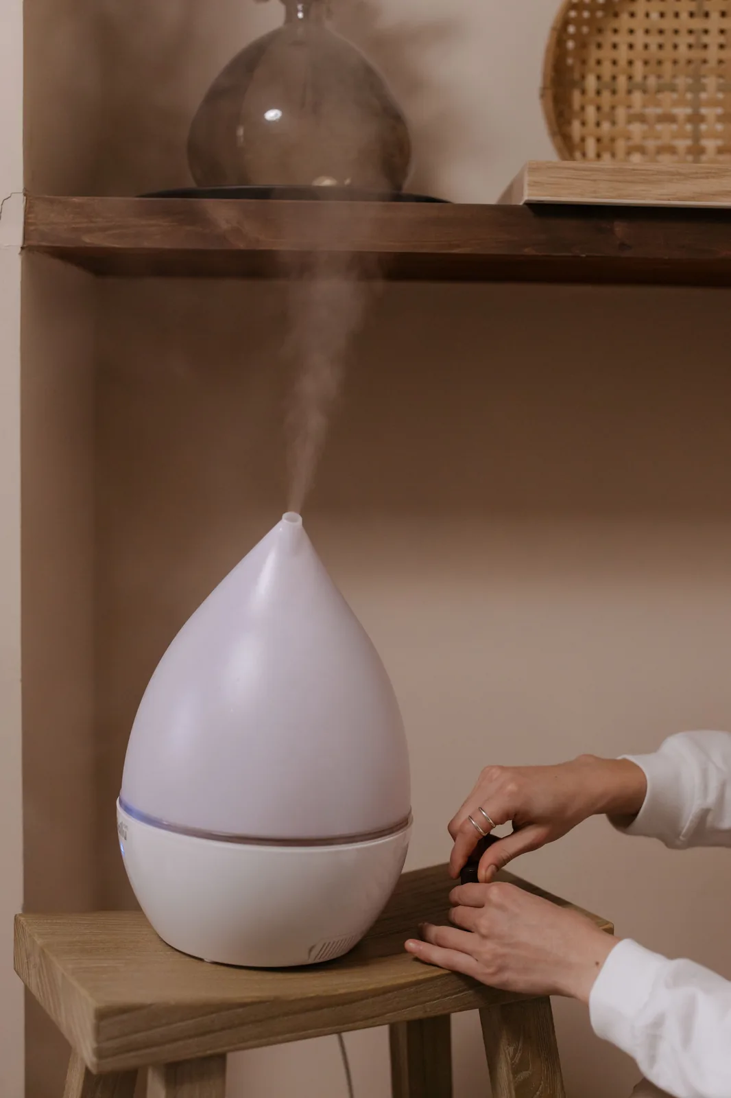 Diffuseur à ultrasons en fonctionnement, réglé à la main sur une étagère en bois