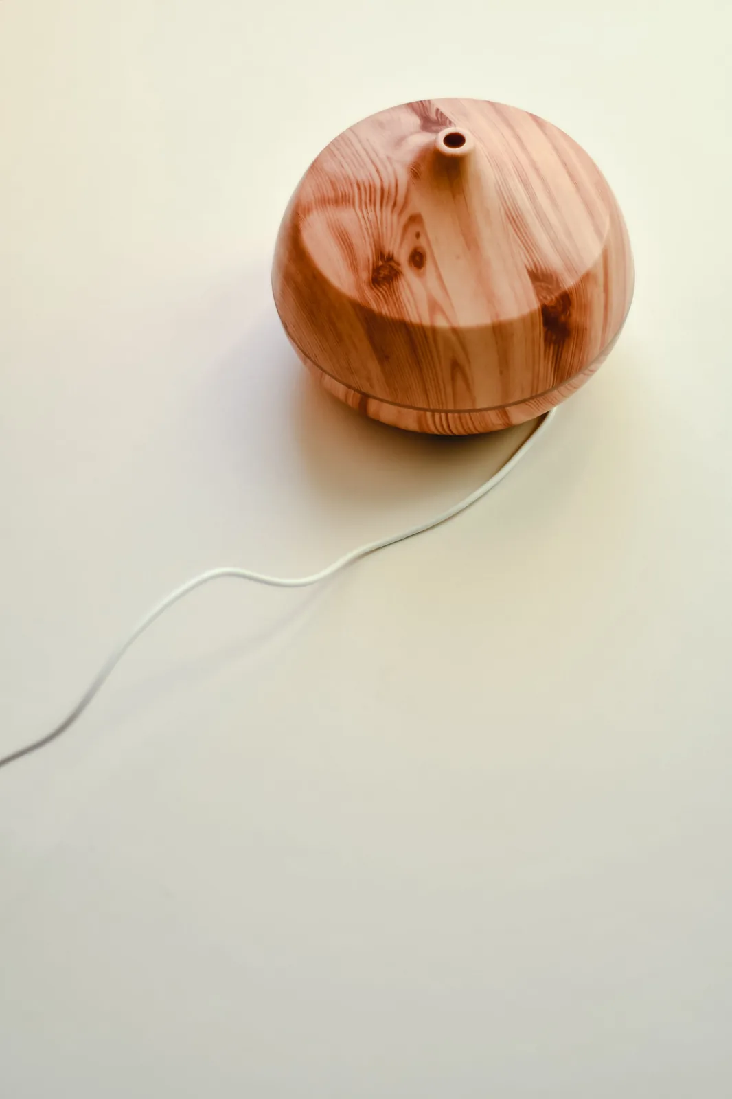 Diffuseur en bois posé sur une surface claire, câble d'alimentation visible