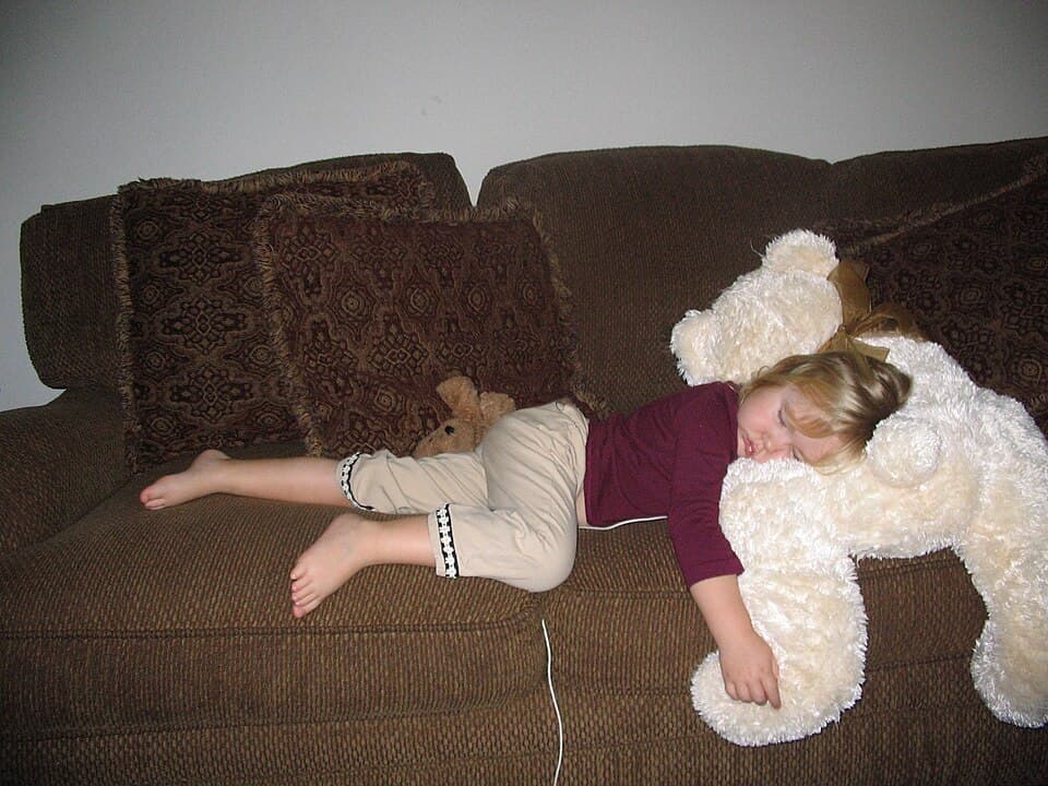 enfant dormant sur le canapé avec un doudou